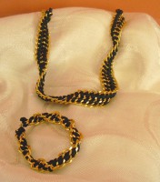 Conjunto pulsera y collar negro con cadena dorada.